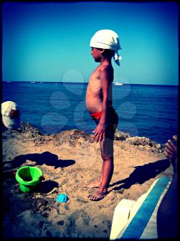 grungy vintage photo - little boy on a beach